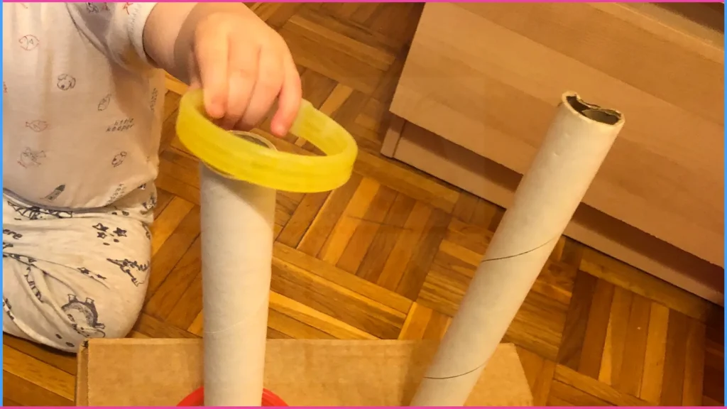 Fűzős játékok - Kisfiú karikát tesz a papír gurigára